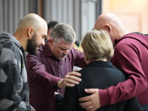 Pastor Greg Locke praying with people